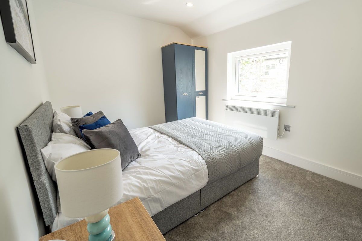 A neatly arranged bedroom with a bed, bedside lamp, and a wardrobe.