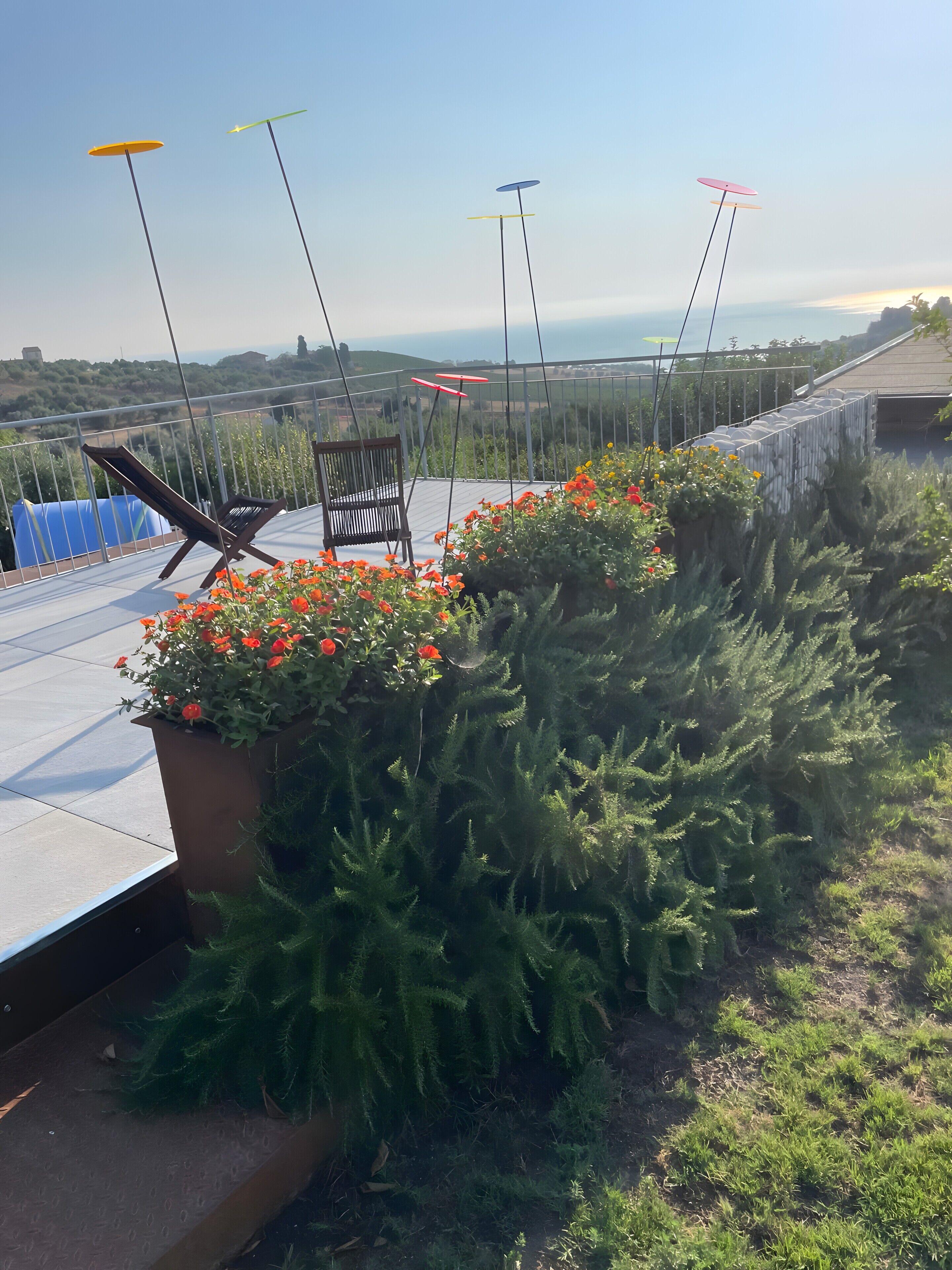 Eine Dachterrasse mit Stuhl, Topfpflanzen und Blick auf die Landschaft.