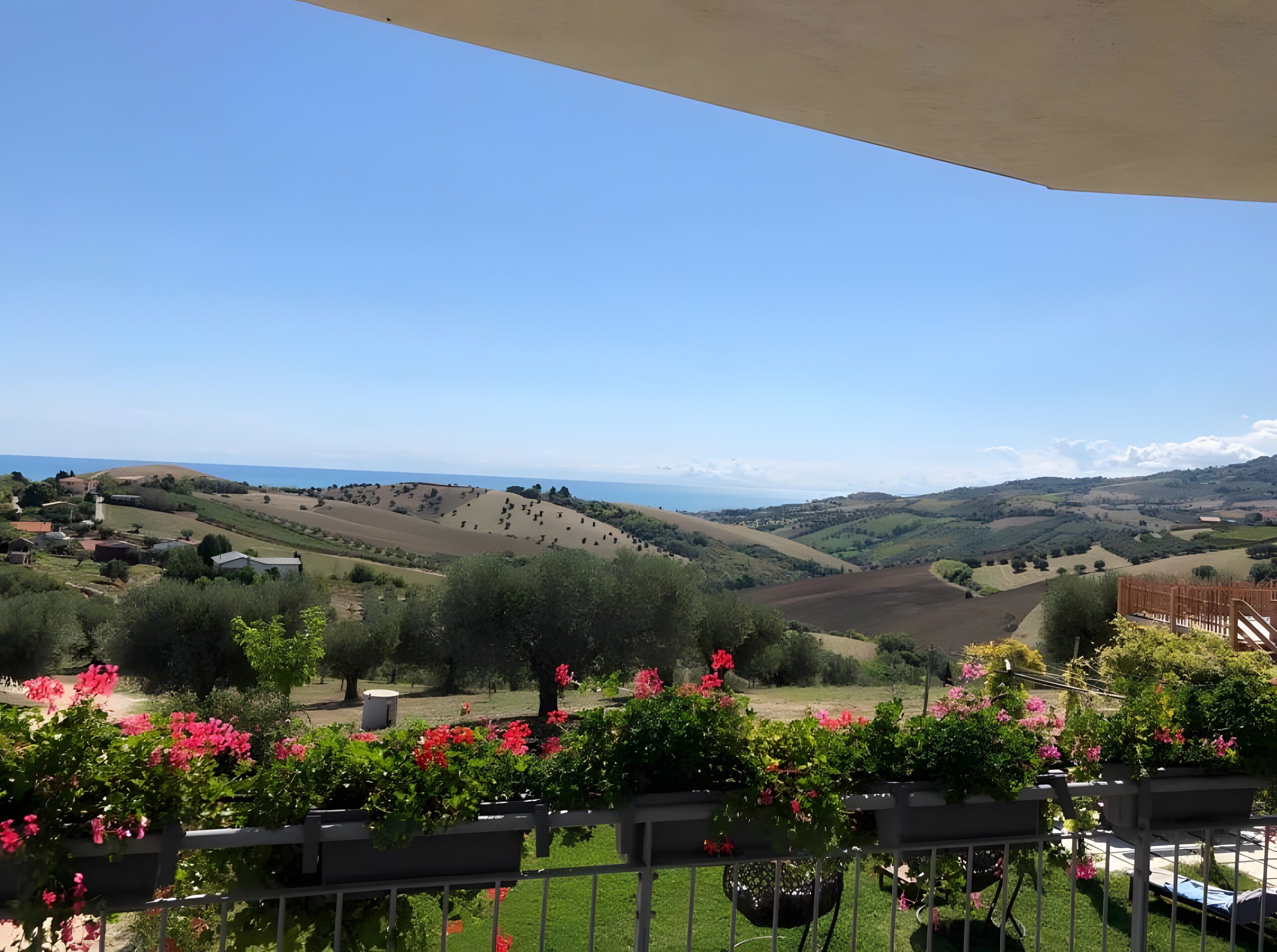 Eine Terrasse mit Blick auf sanfte Hügel und das Meer.