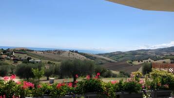 Eine Terrasse mit Blick auf sanfte Hügel und das Meer.