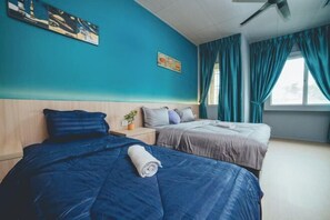 Ein Hotelzimmer mit zwei Betten, türkisgrünen Wänden und einem Deckenventilator.