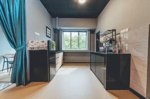 Una cocina moderna con ventana, un comedor con una silla y una encimera con electrodomésticos.