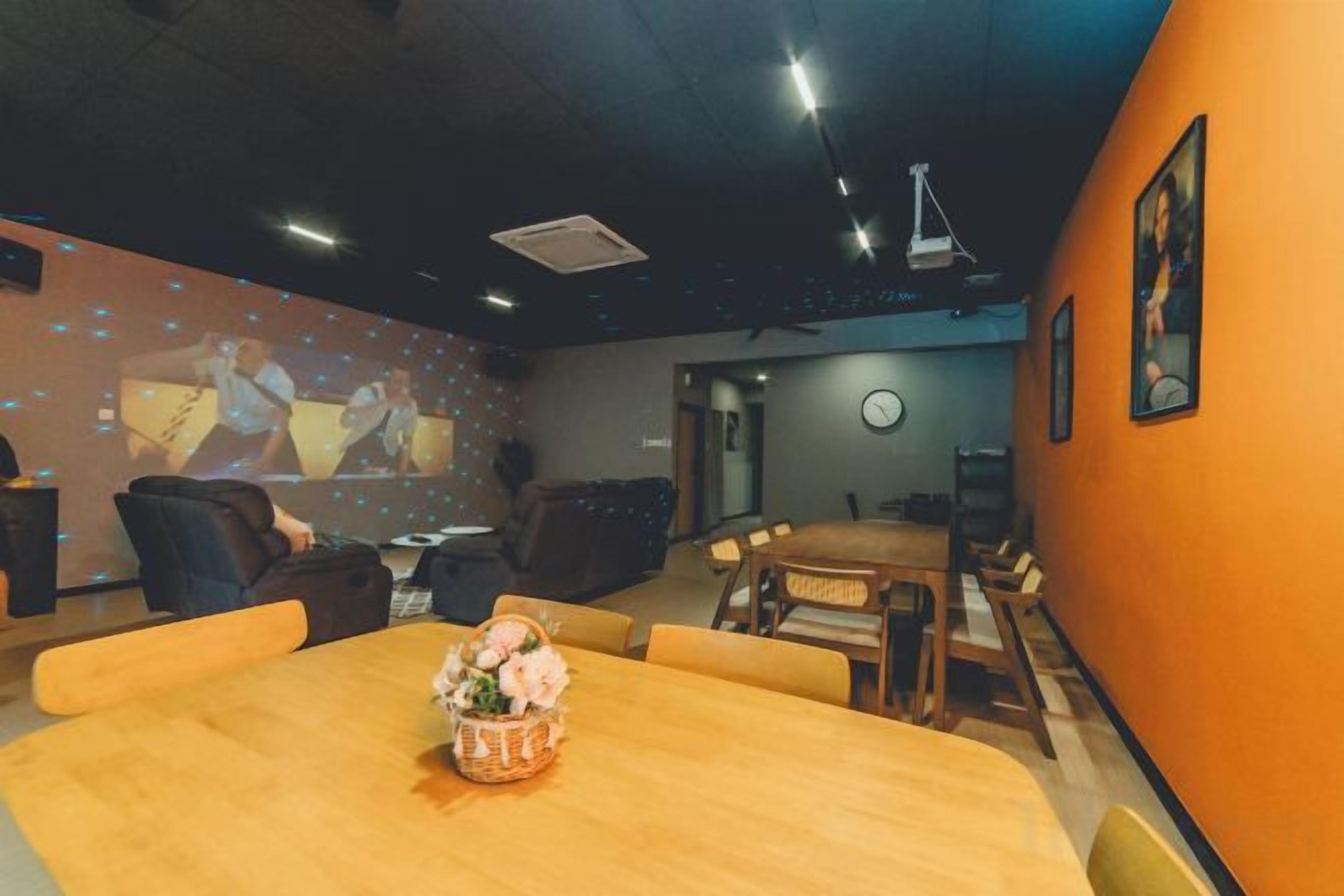 A conference room with a wooden table, chairs, a projector screen, and a clock on the wall.