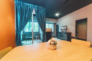Una habitación con una mesa de madera, una cesta de flores y vistas al exterior a través de amplios ventanales.