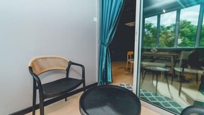 A balcony with a wicker chair, a round black table, and a view of an outdoor dining area through glass doors. - Austin Shoplot Grand KTV Party 15pax Mahjong Chill (Tebrau)
