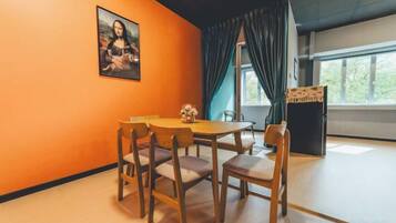A room with a dining table, chairs, a painting on the wall, and a window with curtains.