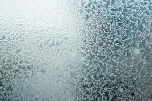 Una ventana de vidrio empañada con intrincados diseños formados por la escarcha.