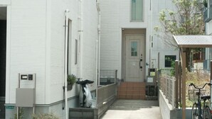 A modern building with a clean, white exterior, a small entrance with steps, and a bicycle parked outside.