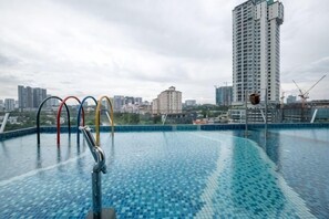 A swimming pool with multiple diving boards, a city skyline in the background, and a tall building. - Bliss Residence Old Klang Road by FEEL HOME (Kuala Lumpur)