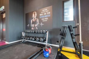 A gym with weightlifting equipment, a motivational poster, and a kettlebell. - Bliss Residence Old Klang Road by FEEL HOME (Kuala Lumpur)