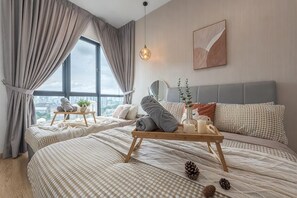 Un dormitorio con dos camas, vistas a la ciudad, una mesita de noche con lámpara y una ventana con cortinas.