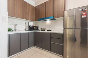 A modern kitchen with dark cabinets, a stainless steel refrigerator, and a coffee maker. - Bliss Residence Old Klang Road by FEEL HOME (Kuala Lumpur)