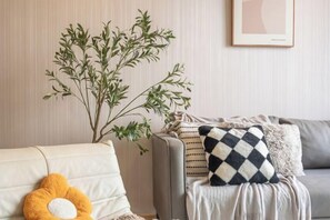 A living room with a sofa, a plant, and a framed picture on the wall. - Bliss Residence Old Klang Road by FEEL HOME (Kuala Lumpur)