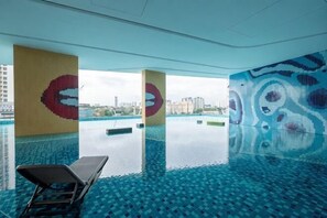 A modern indoor swimming pool with a clear view of the city skyline. - Bliss Residence Old Klang Road by FEEL HOME (Kuala Lumpur)