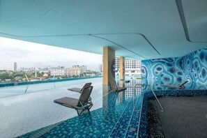 Piscina interior con sillas de descanso y vista panorámica de la ciudad.