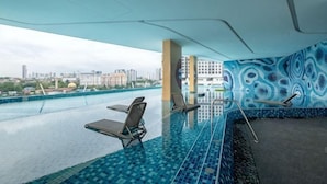 An indoor swimming pool with a city view, lounge chairs, and a patterned wall. - Bliss Residence Old Klang Road by FEEL HOME (Kuala Lumpur)