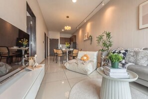 A modern living room with a sofa, a coffee table, and a dining area in the background. - Bliss Residence Old Klang Road by FEEL HOME (Kuala Lumpur)