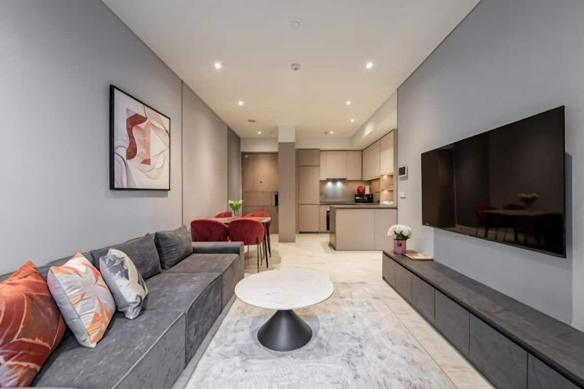 Een moderne woonkamer met een bank, salontafel en een aan de muur bevestigde televisie.