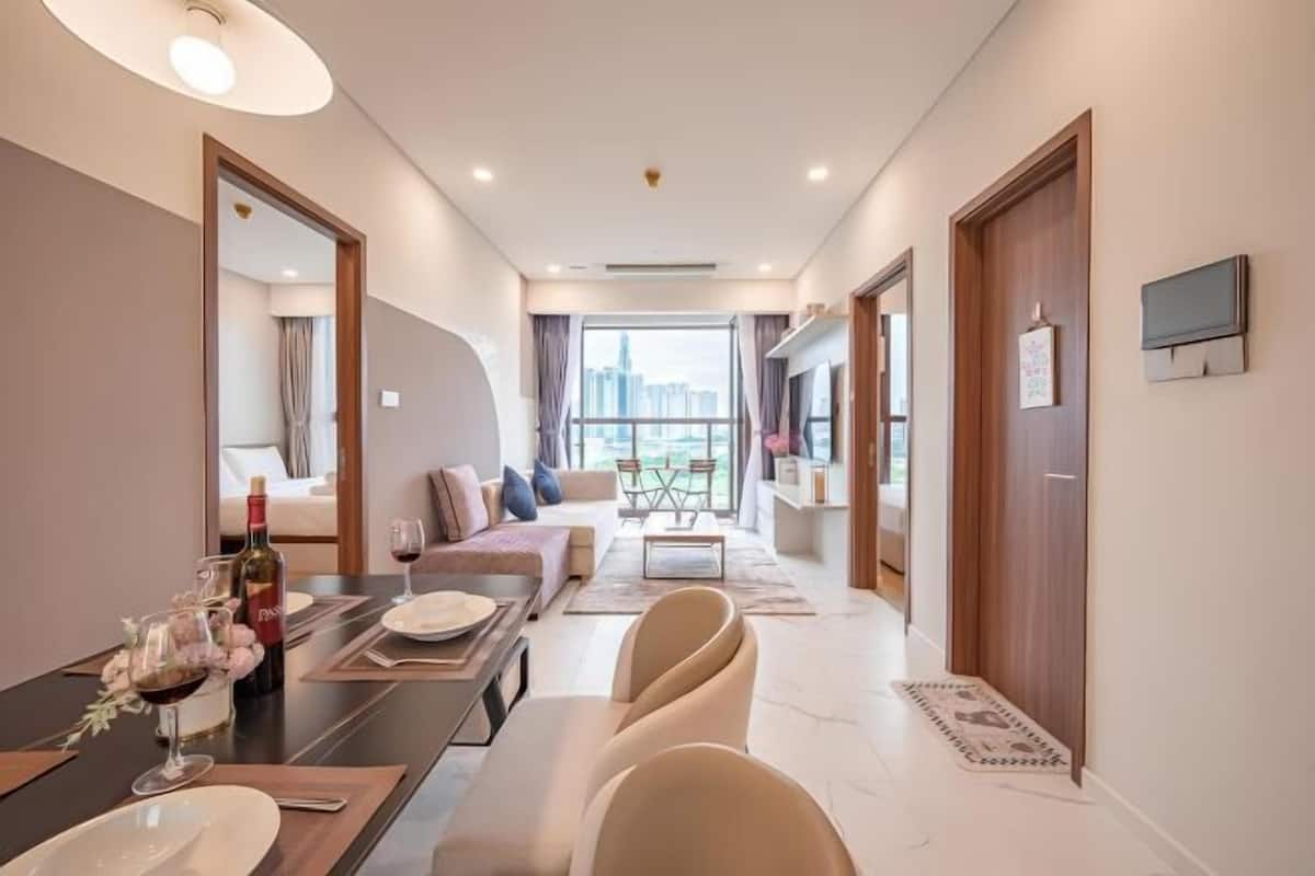 Een moderne hotelkamer met een zithoek, een groot raam met uitzicht op de stad en een flatscreen televisie aan de muur.