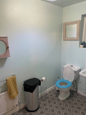 A bathroom with a toilet, a trash bin, a towel rack, and a mirror. - Family Home Near the Beach (Lytham St. Anne's)