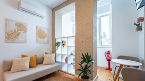 A modern living room with a sofa, a dining table, a potted plant, and a fire extinguisher. - Nomad s Easy Stay - Duque Studio XIX (Porto)