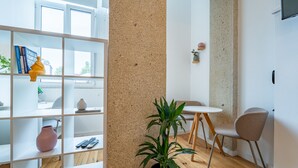 A modern living room with a white bookshelf, a potted plant, a small round table, and two chairs. - Nomad s Easy Stay - Duque Studio XIX (Porto)