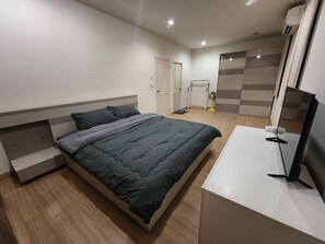 A modern bedroom with a bed, bedside tables, a TV, and a walk-in closet. - Spacious Entire House With Shared Fitness Room and Shared Indoor Pool in Club (Pathum Thani)