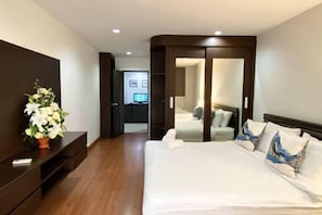 Una habitación de hotel con una cama grande, un aparador de madera, un televisor y un espejo.