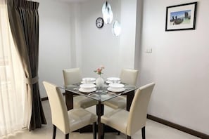 A dining area with a glass table, four chairs, a vase with flowers, and a clock on the wall. - 14Place Sukhumvit Villa @ Terminal 21 Bangkok (Bangkok)