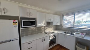 Una cocina compacta con gabinetes blancos, un microondas, una estufa y un lavaplatos.