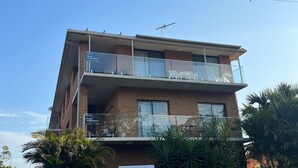Un edificio de dos pisos con balcones, una antena parabólica y carteles que indican alojamiento vacacional.