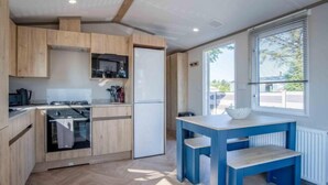 Una cucina moderna con mobili in legno, forno a incasso e zona pranzo con tavolo e panca blu.