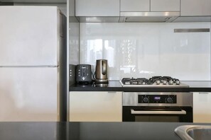 A modern kitchen with a stainless steel refrigerator, a coffee maker, a gas stove, and an oven. - A Modern 2BR Apt with City Views, FREE Parking (Southbank)