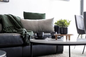 A modern living room with a sofa, a coffee table, and a potted plant. - A Modern 2BR Apt with City Views, FREE Parking (Southbank)
