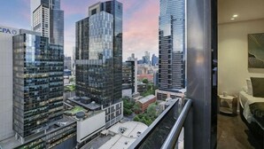 A high-rise building with a modern glass facade, a view of the cityscape, and a balcony with a railing. - A Modern 2BR Apt with City Views, FREE Parking (Southbank)