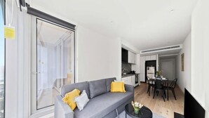 Een moderne woonkamer met een bank, een eettafel en een keuken op de achtergrond.