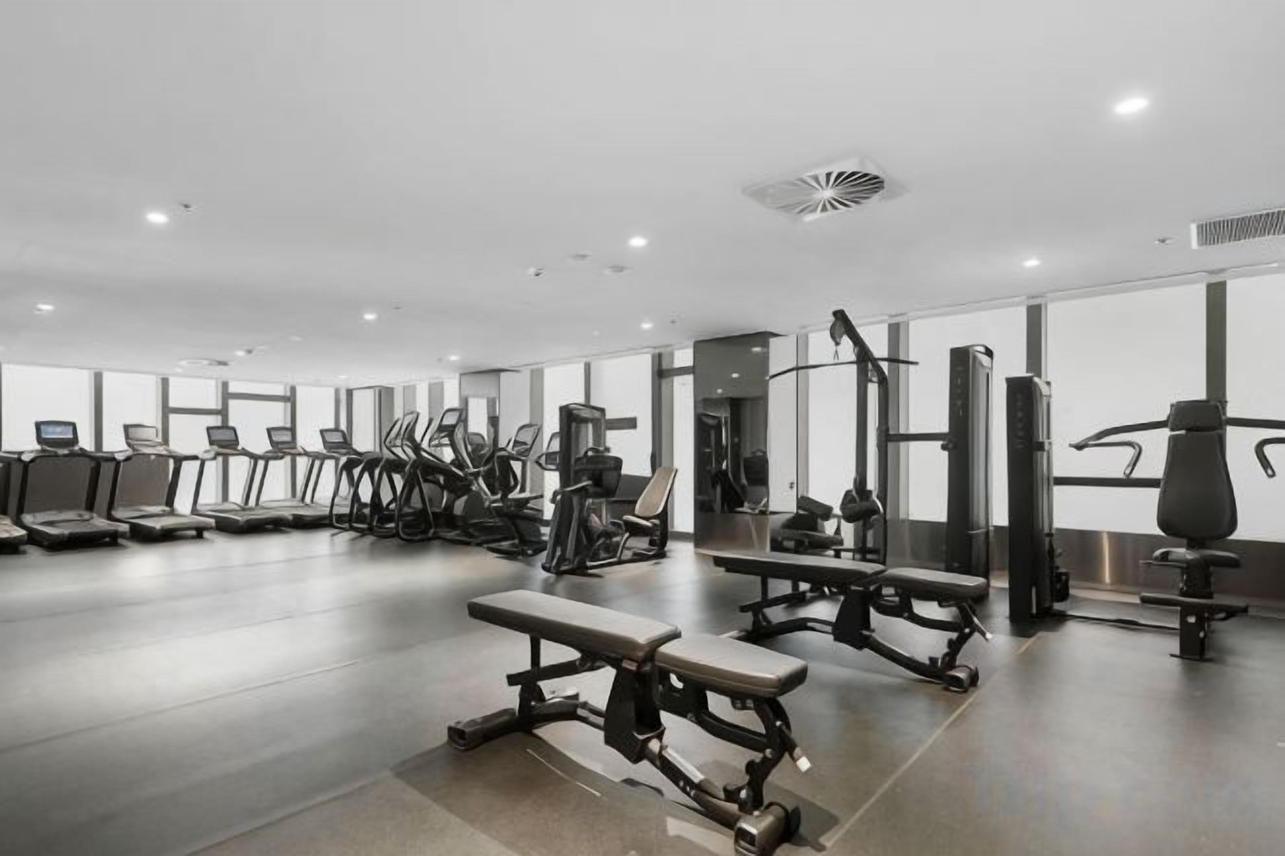 A gym with treadmills, weight machines, and benches.
