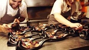 Een kok bereidt eten in een professionele keuken met roestvrijstalen oppervlakken en speciaal kookgerei.