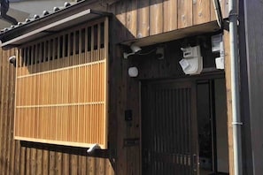 A wooden building with a sliding door and a window with vertical blinds. - KIRAKU・ENRINON (Kyoto)