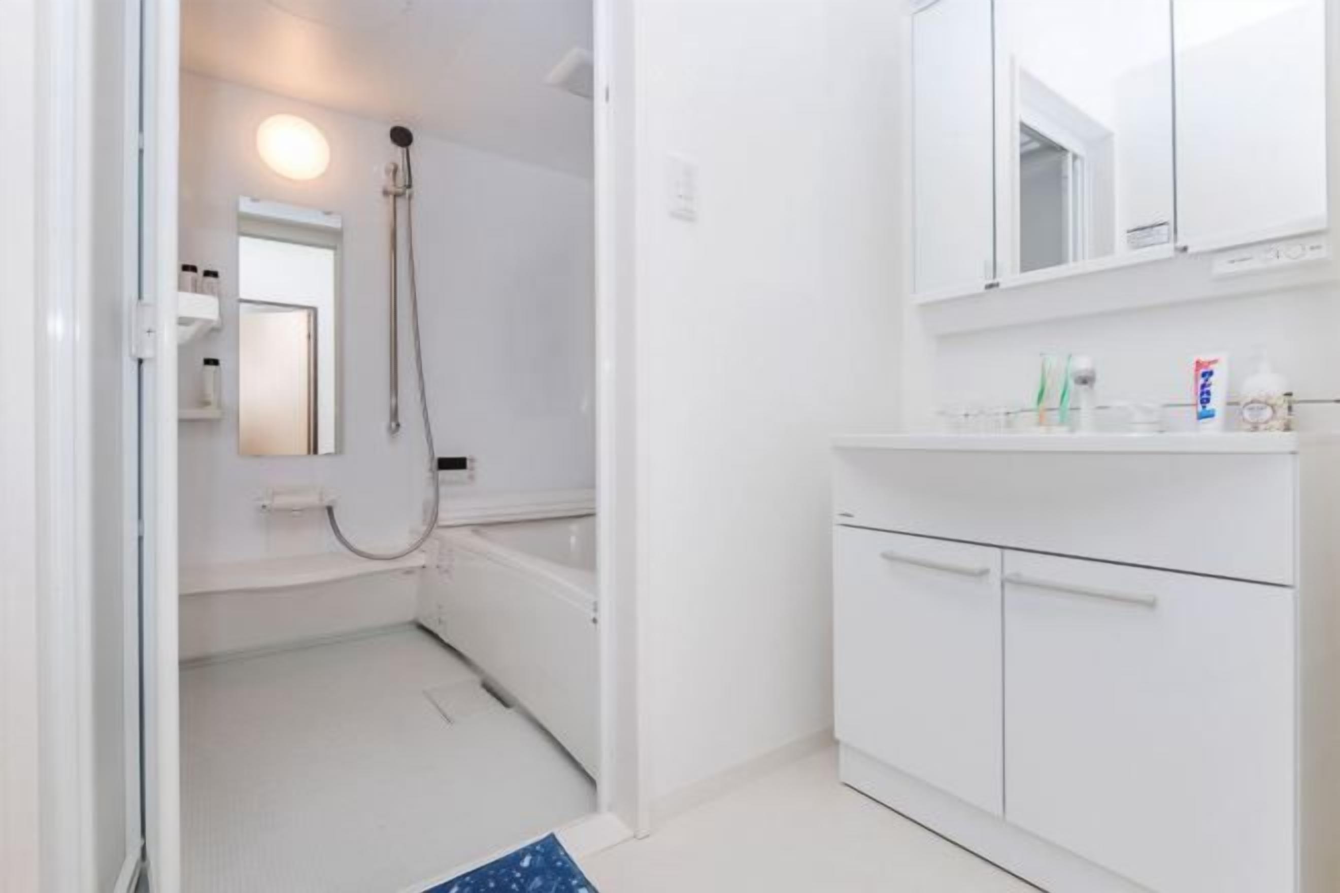 A modern bathroom with a white sink, mirror, and shower.