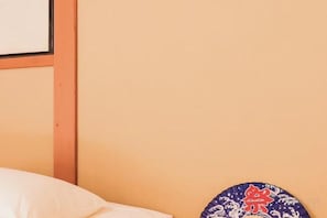 A bed with a white pillow and a wall with a framed picture. - KIRAKU・ENRINON (Kyoto)