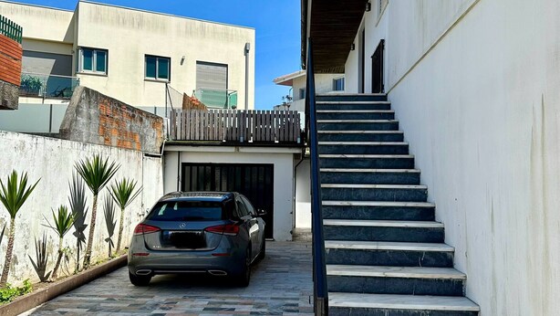 A modern building with a car parked in front, a staircase, and a tiled pavement. - 7 Room House, 2 Kitchens (Vila Nova de Gaia)