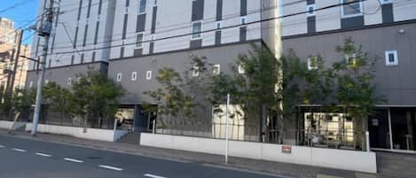 Un immeuble à plusieurs étages doté d’une façade plate, d’un passage piéton et d’une rue où aucun véhicule n’est visible.