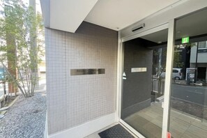 Een hotelingang met een betegelde muur, een glazen deur en een bord met de naam 'Regno Confort Hotel'.