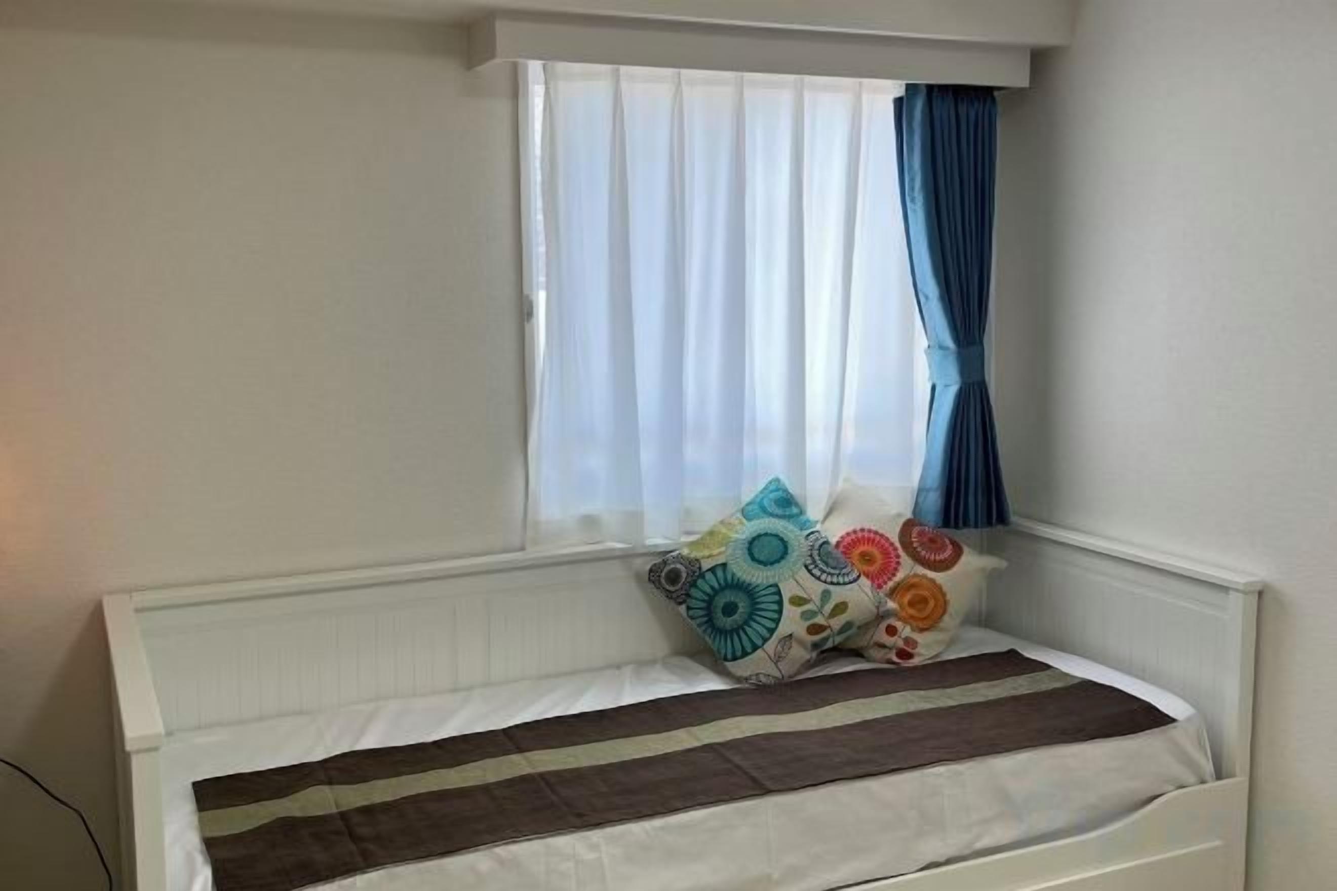 A bed with a striped blanket, a window with curtains, and decorative pillows.