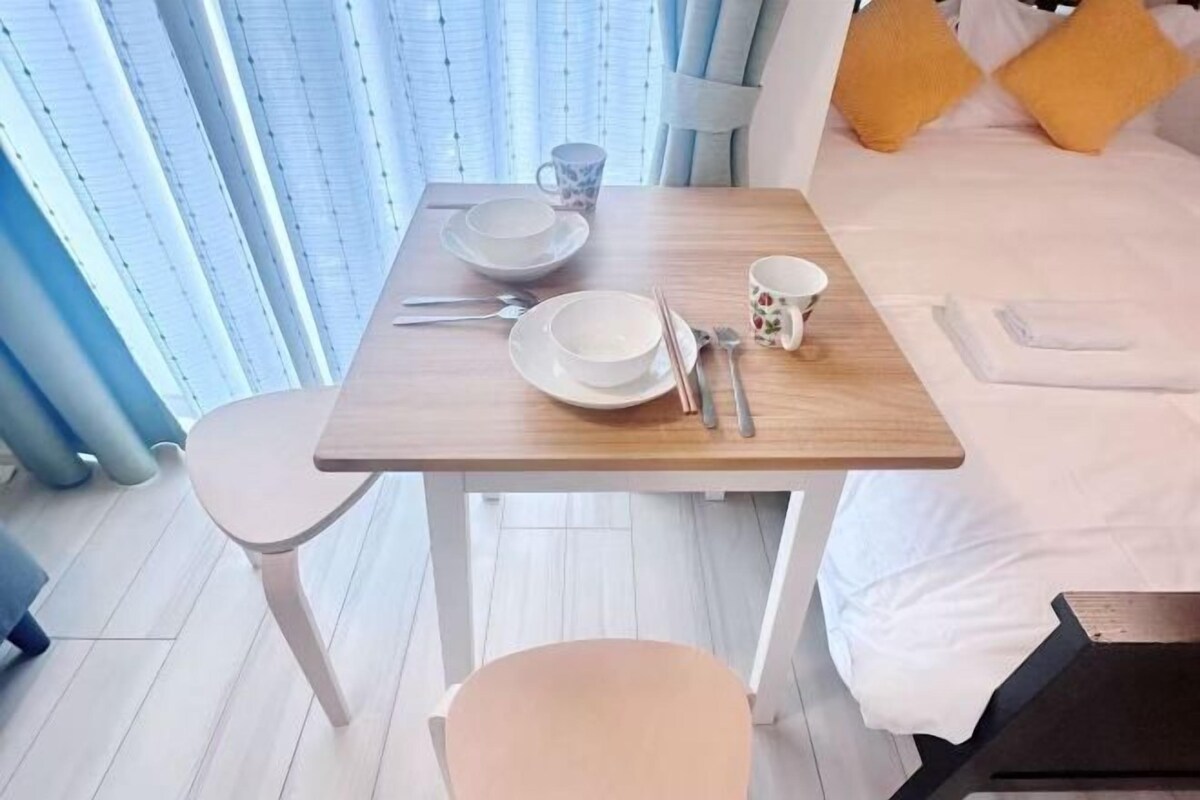 A neatly arranged dining area with a table set for two, including plates, cutlery, and a cup.