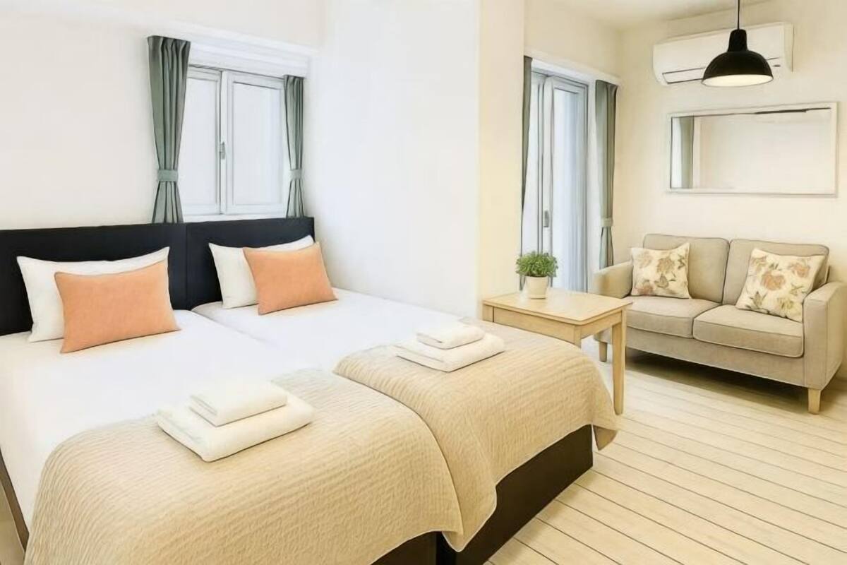 A hotel room with a bed, a sofa, a small table, and a window with curtains.