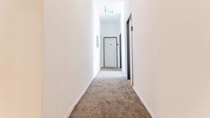 A narrow hallway with a carpeted floor, white walls, and a door at the end. - 6BR Apt with Garden near Danube (Vienna)