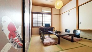 A tatami mat room with a low table, cushions, a hanging light fixture, and a sliding door. - Guesthouse Kinoya (Kyoto)