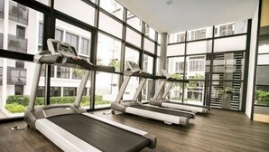 A gym with treadmills, large windows, and a modern interior. - Econest Apartment By The One - Educity Ecobotanic (Gelang Patah)